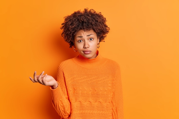 Free Photo horizontal shot of confused hesitant young afro american woman shrugs shoulders looks perplexed and doubtful looks unconfident