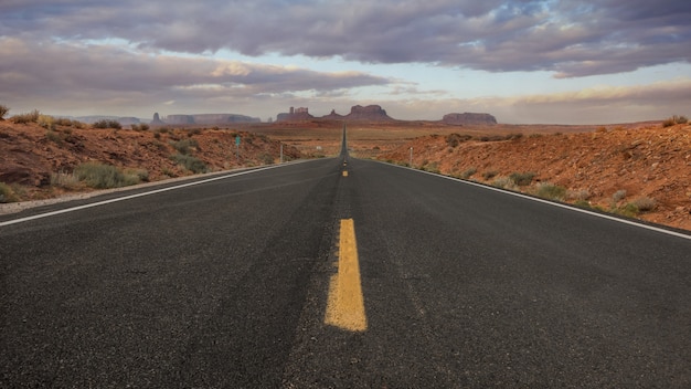 Horizontal shot of an empty road in the Monument Valley, USA with the background of breathtaking sky