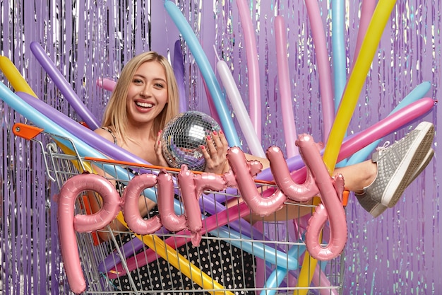 Free photo horizontal shot of glad blonde woman has makeup, holds disco ball