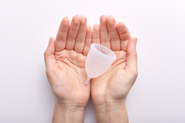 Free Photo horizontal shot of hands putting together over white indoors, holding clean white menstrual cup