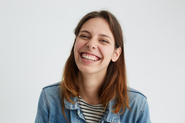 Horizontal shot of playful beautiful young female in good mood having joyful cheerful look, smiling happily, enjoying nice day. Positive human emotions