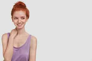 Free photo horizontal shot of pleasant looking ginger female has gentle smile