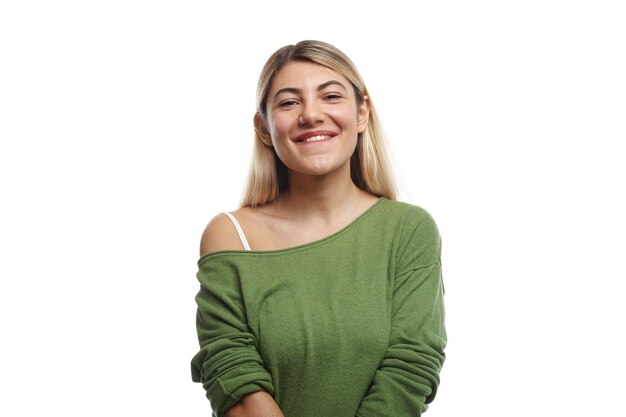 Horizontal shot of positive young European female student with nose ring and dyed hair posing, looking with happy charming smile, feeling relaxed after lectures at university