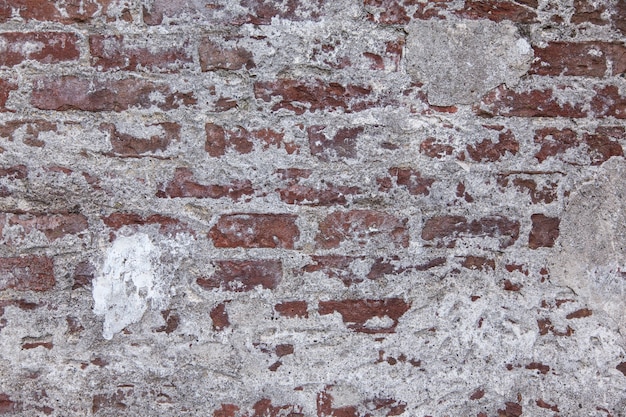 Free photo horizontal shot of a red and white old stone wall with texture and some plaster on it