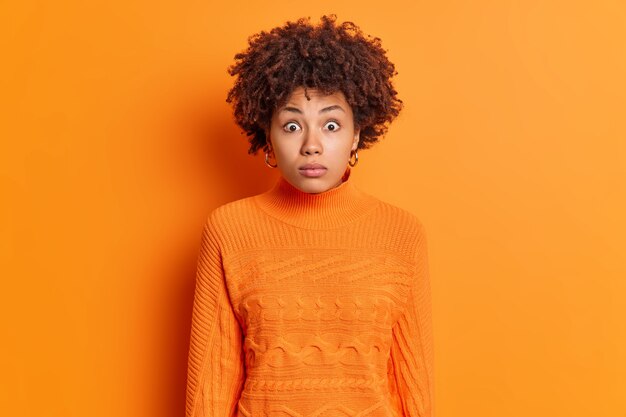 Horizontal shot of shocked African American woman stares at camera with omg expression stunned