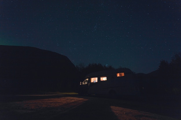 Free Photo horizontal shot of a white vehicle with lights under the beautiful starry sky at night time