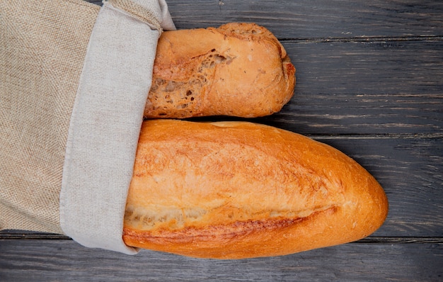 Horizontal view of baguettes as black and vietnamese in sack on wooden surface