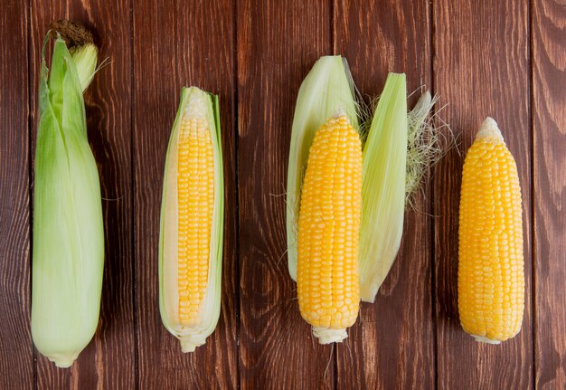 Horizontal view of corn cobs with shell on wooden surface