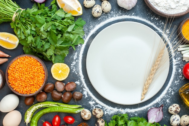 Horizontal view of dinner preparation with eggs fresh vegetables green bundles on dark blue