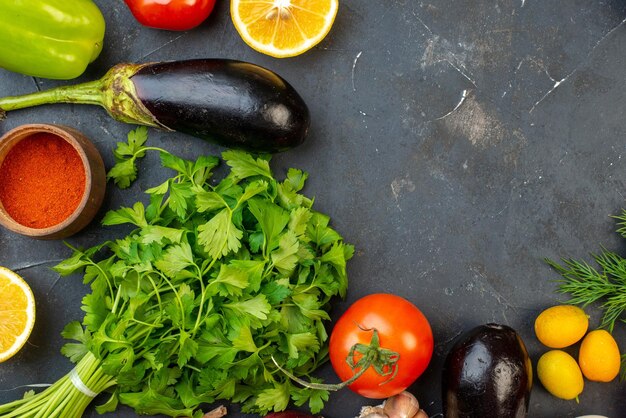 Horizontal view of free space fresh vegetables fallen oil bottle lemons spices green bundles on black table