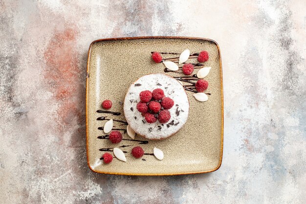 Horizontal view of freshly baked cake with raspberries for babies on a brown tray on white table