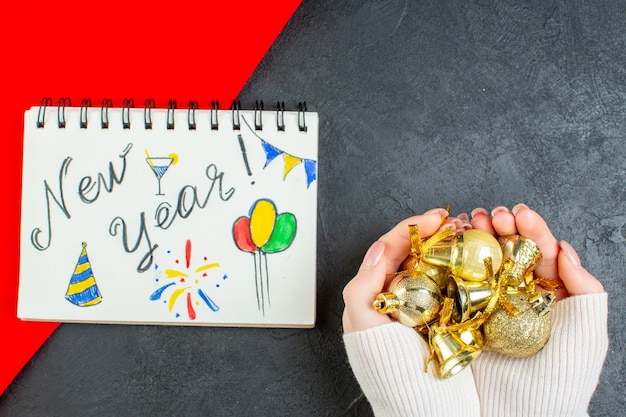 Free Photo horizontal view of hand holding decoration accessories and notebook with new year writing and drawings on dark background