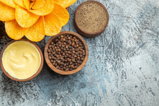 Horizontal view of homemade potato chips decorated like flower shaped and different spices mayonnaise on gray table