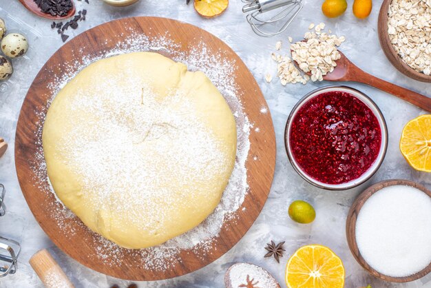 Horizontal view of raw pastry on round wooden board grater and set of foods on ice background