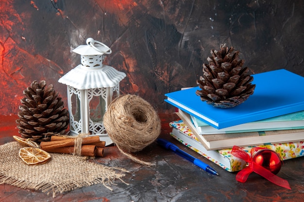 Free Photo horizontal view of stacked notebooks and pen ball of rope cinnamon limes conifer cones on dark background