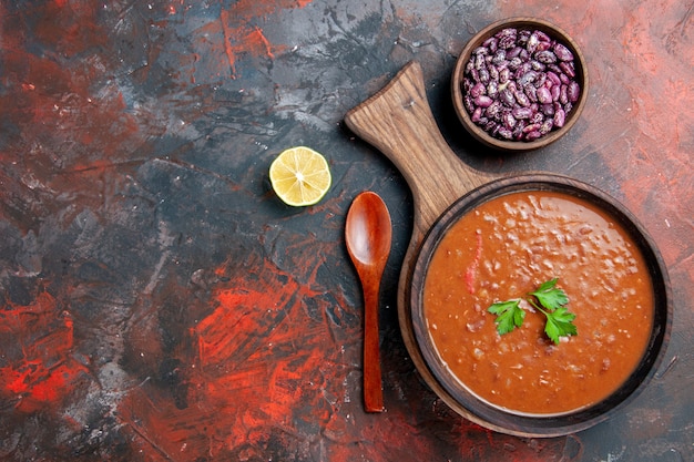 Horizontal view of tomato soup fallen oil bottle beans on cutting board on a mixed color table