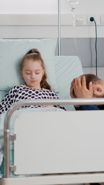 Hospitalized sick daughter sleeping after suffering medical surgery