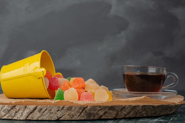 Hot, aroma tea jelly candies on wooden board . 