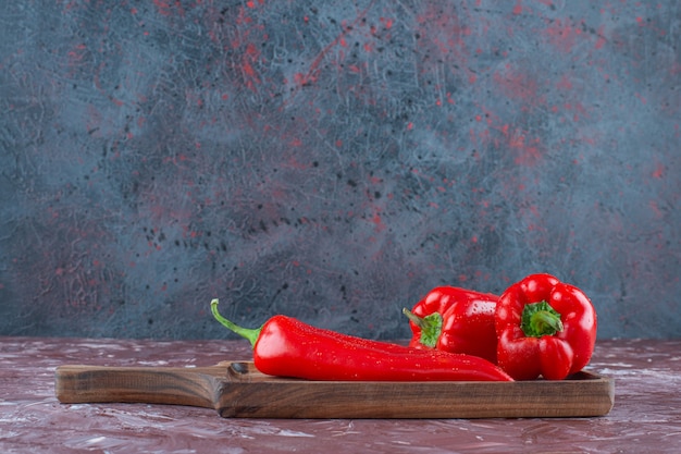 Hot and bell peppers on a board , on the marble background. 