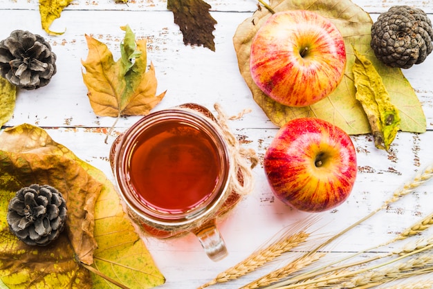 Free photo hot beverage among leaves and apples