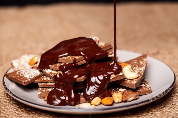 Free photo hot chocolate pouring on candies in white plate sackcloth.