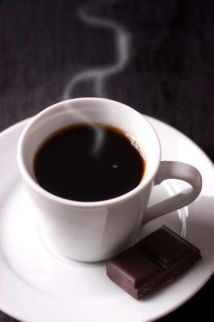 Hot coffee with a piece of chocolate