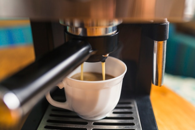 Hot espresso pouring into porcelain mug