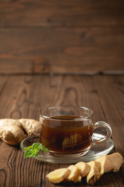 Hot ginger juice and ginger sliced on wooden table.