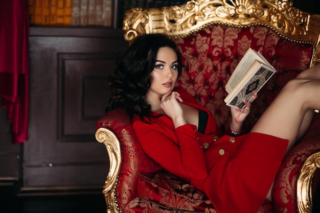 Free photo hot girl in short red dress holding book lying in library