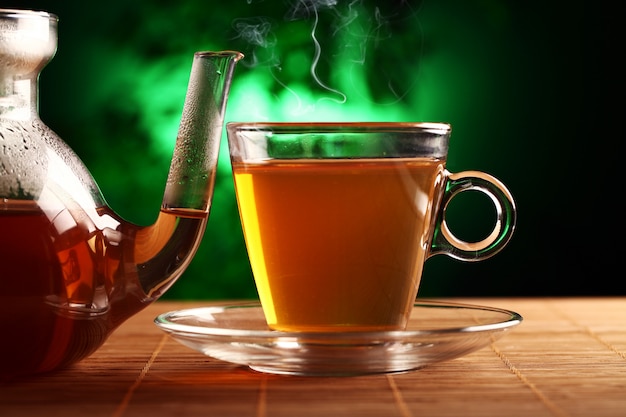 Hot green tea in glass teapot and cup