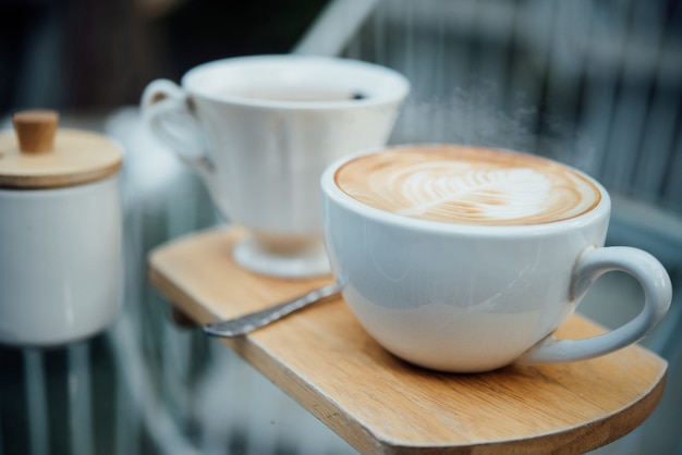 Hot latte art in coffee cup on wood table in coffee shop