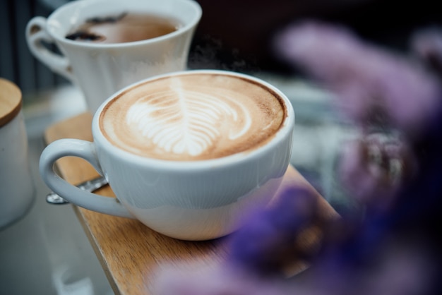 Hot latte art in coffee cup on wood table in coffee shop