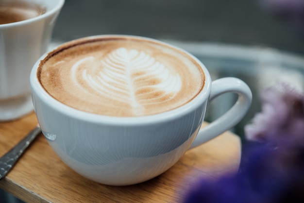 Hot latte art in coffee cup on wood table in coffee shop