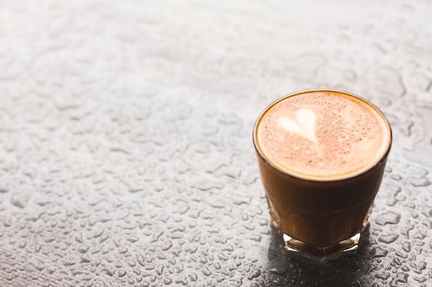 Free Photo hot latte with heart shape in glass on water drop surface