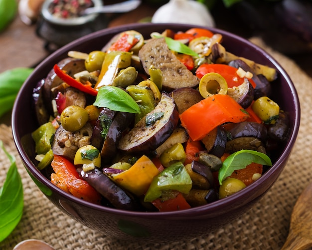 Hot spicy stew eggplant, sweet pepper, olives and capers with basil leaves.