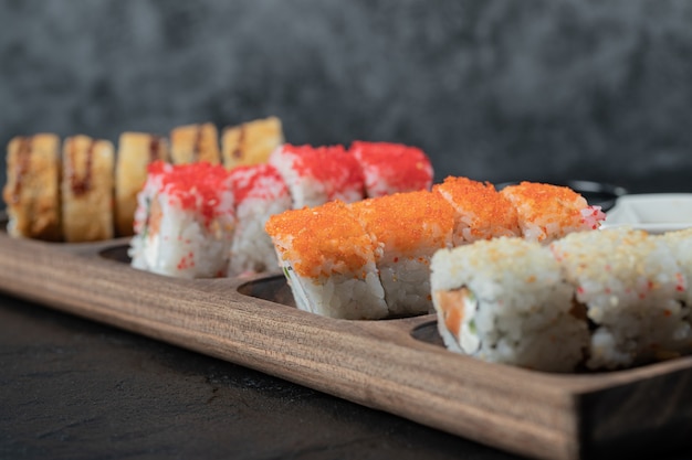 Hot sushi set on a wooden board with mixed ingredients.