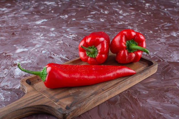 Hot and sweet peppers on a board , on the marble background. 