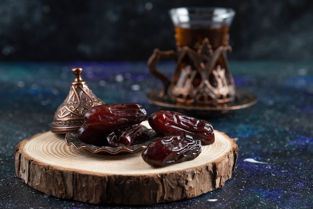 Free photo hot tea behind of dry dates on blue surface