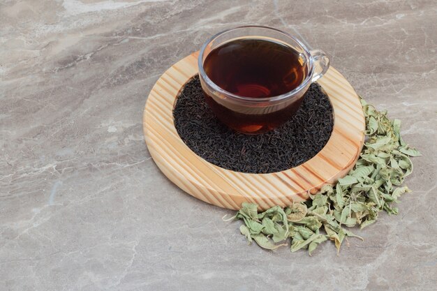 Hot tea with dried leaves on wooden plate .