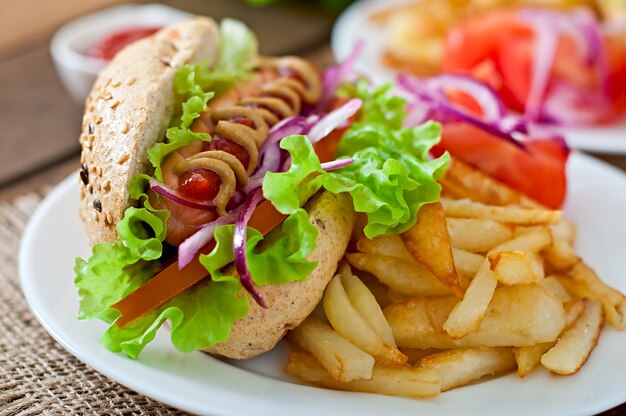 Hotdog with ketchup mustard and lettuce on wooden table.