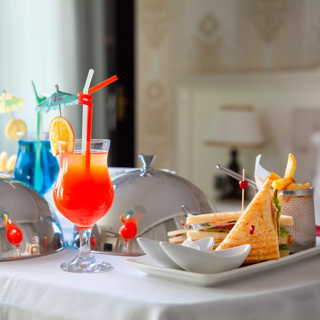 Hotel meal on a table with sandwich, hamburger, cocktails and others in bedroom side view