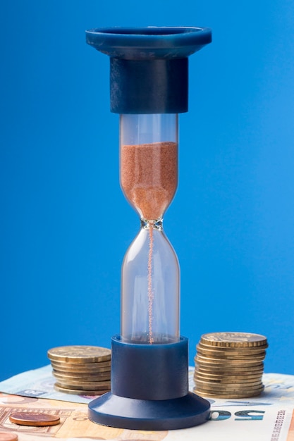 Free Photo hourglass next to pile of coins arrangement