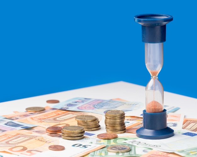 Hourglass next to pile of coins