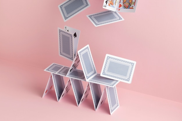 Free photo house of cards falling on pink background