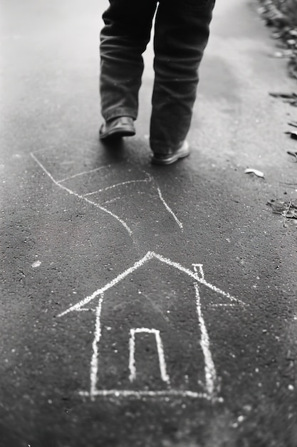 House drawn with chalk on the road by a man