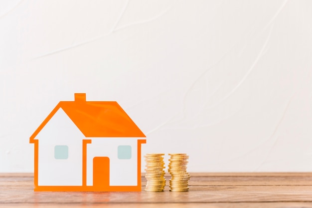 House and stacked coins on wooden table