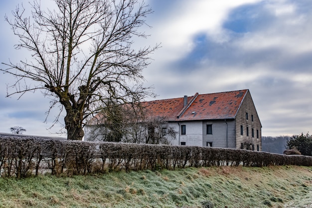 Free photo house surrounded by greenery with hills under a cloudy sky on the background