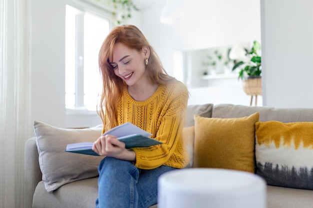 Household humidifier at home on table near woman reading on sofa