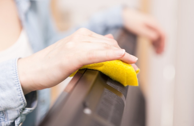 Free photo housewife cleaning the dust of tv in living room