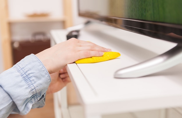 Housewife cleaning dust of tv stand in living room